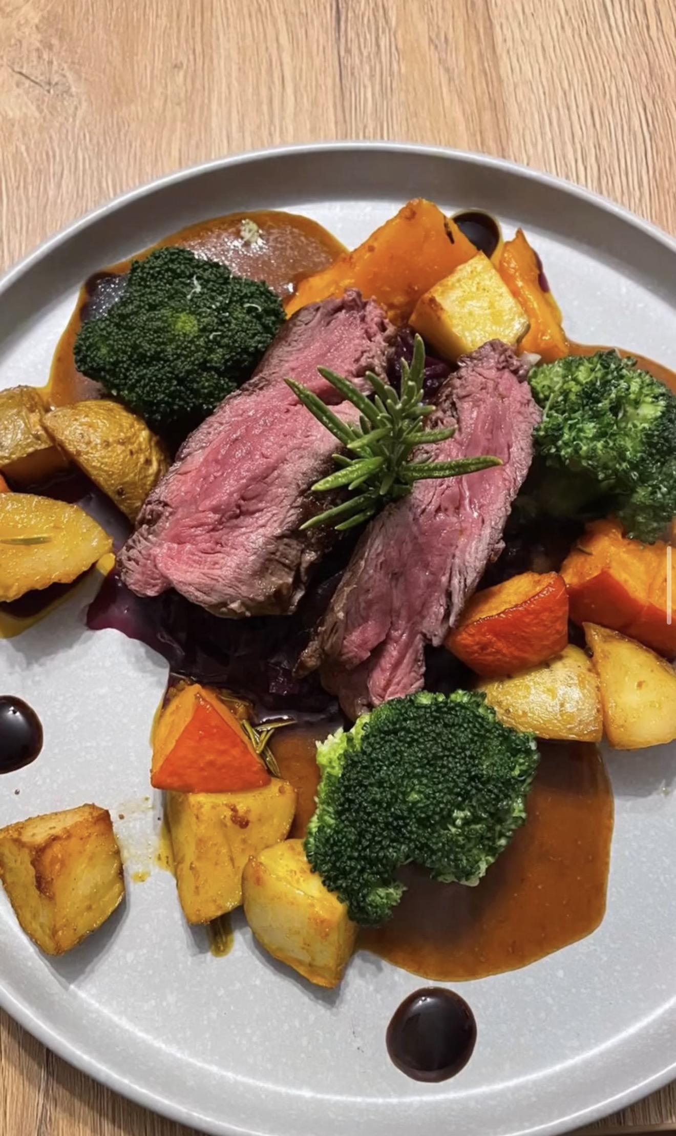 Rosa gegartes Fleisch mit Gemuese und Sauce.
